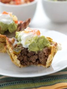 some tacos are sitting on a plate with guacamole and sour cream