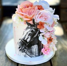 there is a cake decorated with flowers and a horse on the top, sitting on a wooden table