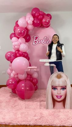 a barbie doll is standing next to a pink balloon arch