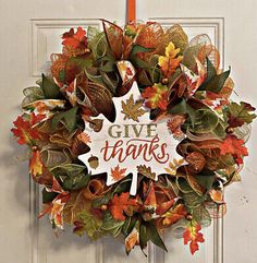 a wreath that says give thanks hanging on a door with leaves and acorns