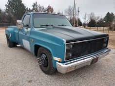 an old blue truck parked in a gravel lot