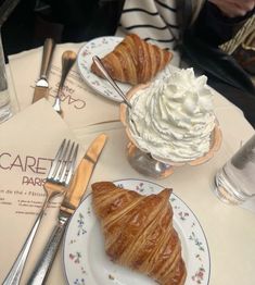 there are two croissants on the plates and one has whipped cream on it