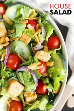 a salad with lettuce, tomatoes and croutons is shown in a white bowl