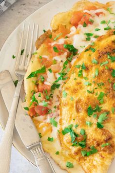 a white plate topped with an omelet covered in cheese and veggies