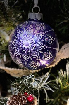 an ornament hanging from a christmas tree with pine cones and berries on it