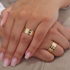 two hands holding each other with gold rings on their fingers and manicured nail polish