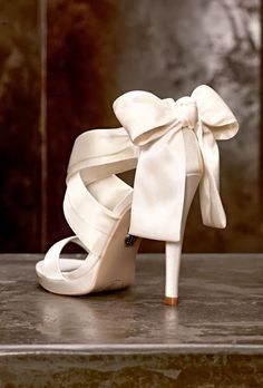 a white high heeled shoe with a bow on the side