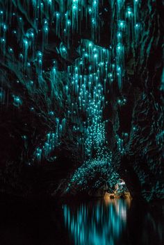 the inside of a cave with green lights hanging from it's walls and water