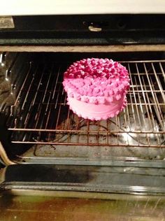 a pink cake sitting in an oven on top of a wire rack with the door open