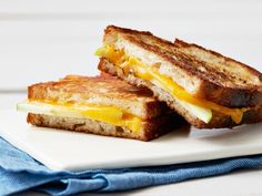 two grilled cheese sandwiches sitting on top of a white plate next to a blue napkin