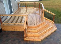 a wooden deck with steps and railings next to a house