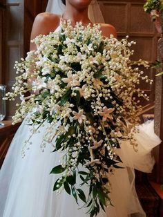 a bride holding a bouquet of white flowers in her wedding dress at the alters