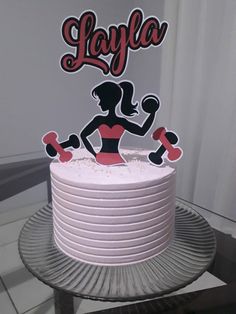 a cake with a woman holding dumbs on top of it and the word layla written in large letters