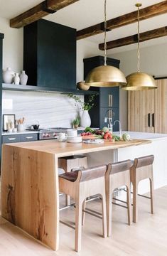 a kitchen with wooden floors and black cabinets, two pendant lights hanging from the ceiling