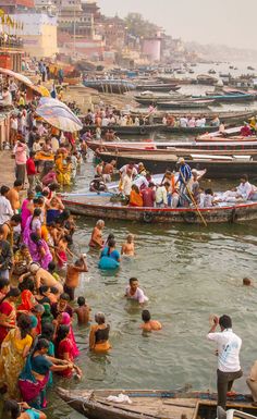 many people are bathing in the water near boats