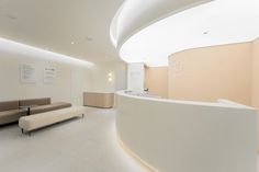 the interior of a modern office building with curved walls and white flooring, along with two couches