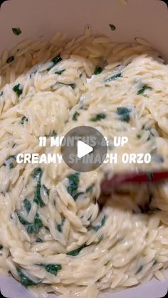 a bowl filled with pasta and spinach on top of a table