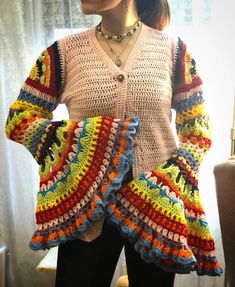 a woman standing in front of a window wearing a multicolored sweater