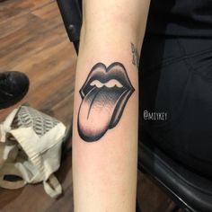 a woman's arm with a tattoo of a rolling tongue on it, in black and white