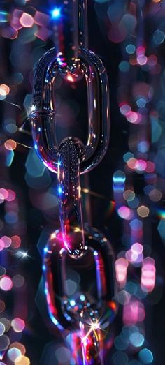 an abstract image of a chain hanging from the ceiling with colorful lights in the background