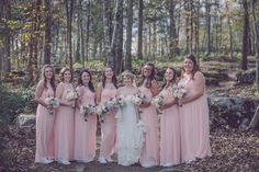 a group of women standing next to each other in front of trees and leaves on the ground