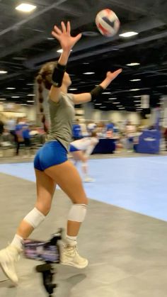 a woman is playing volleyball in an indoor court while people watch from the sidelines