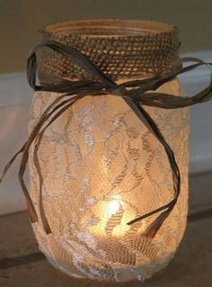 a mason jar filled with lace and a lit candle