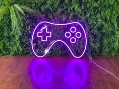 a video game controller neon sign sitting on top of a wooden floor next to a green wall