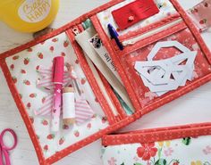 two red trays with pens, scissors and other crafting supplies in them on a table