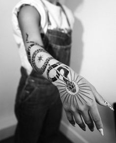 a woman with tattoos on her arm and hand is holding something in the other hand