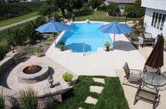 an aerial view of a pool and patio with umbrellas over the fire pit area