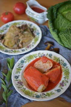 two plates filled with food on top of a table next to some vegetables and sauce