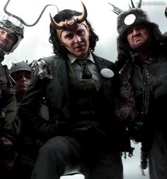 three men dressed in costumes with horns on their heads and one man wearing a suit