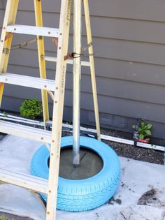 an old tire is being used as a planter in front of a house with a ladder