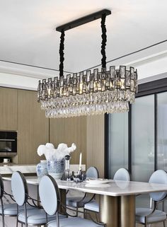 a chandelier hanging from the ceiling in a dining room with chairs around it