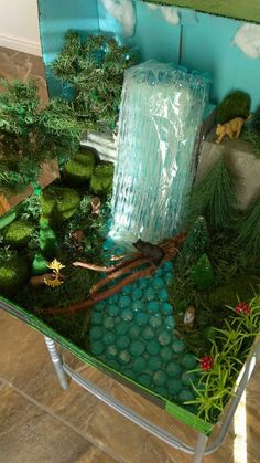 a table that has some plants and rocks in it on top of the table is a water fall