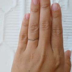 a woman's hand with a diamond ring on top of her left hand, showing the middle finger