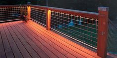 a wooden deck with metal railing and planter on it at night, in the evening