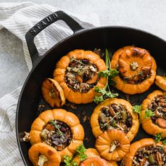 baked stuffed pumpkins in a skillet with herbs and nuts on the top, ready to be eaten