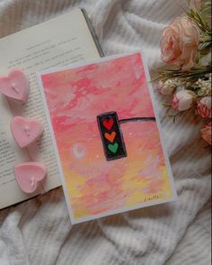 an open book with hearts on it next to some pink flowers and other things in the background