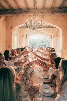 a group of people sitting at a long table with wine glasses in front of them