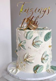 there is a wedding cake with flowers on the top and two gold rings on top