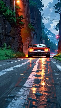 a car driving down a wet road next to a lush green tree covered hillside at night