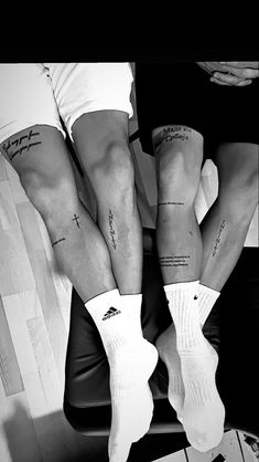 three people with tattoos on their legs sitting in a chair