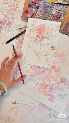 someone is painting flowers with watercolors on paper