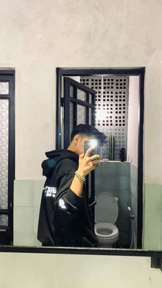 a man taking a selfie in front of a bathroom mirror with his cell phone