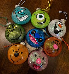 there are many ornaments that have been painted to look like cartoon characters on them, all in different colors and shapes