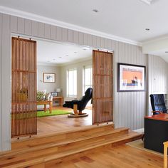 an office with wood floors and white walls is seen through the open doors to another room