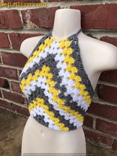 a white mannequin wearing a yellow and gray crocheted halter top