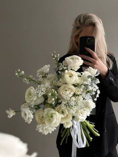 a woman taking a selfie with her cell phone while holding a bouquet of flowers